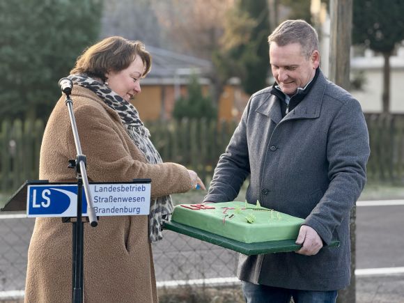 Ortsvorsteher Carstn Höger übergibt als Dankeschön einen Kuchen an Dr. Ina Bartmann. (Foto: Gina Werthe/ LK Prignitz)