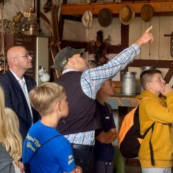 Schmiedemeister Mike Riegert zeigt den Kindern die Werkzeuge und Geräte, die früher auf einem Hof täglich genutzt wurden. Auch Landrat Christian Müller hörte interessiert zu.