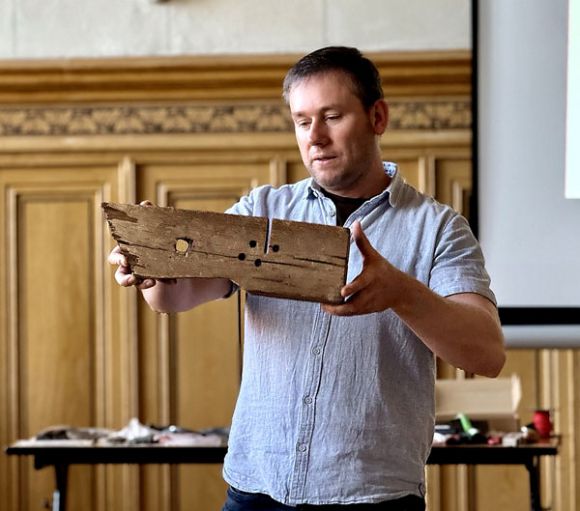 Gordon Thalmann präsentiert ein Stück Konstruktionsholz aus einem historischen Dachstuhl. / Foto: LK Prignitz, Gina Werthe